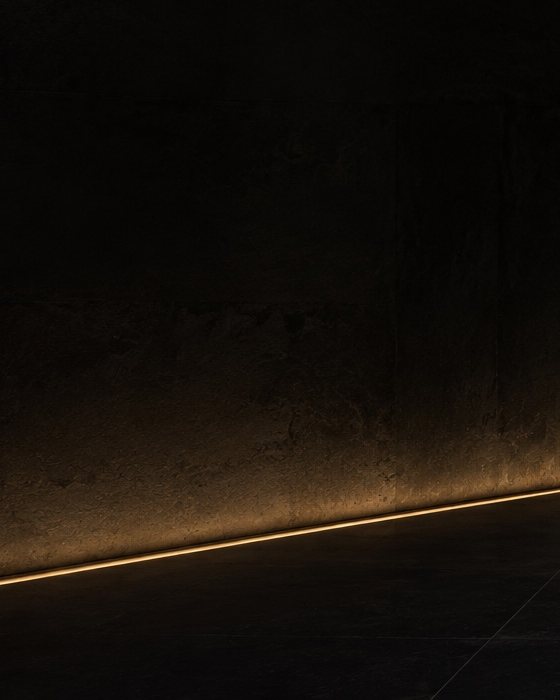 Mur sombre souligné au sol par un mince filet de lumière dorée