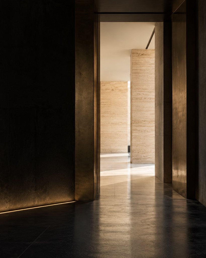 Passage architectural plongé dans l’ombre, ouvert sur un seuil de travertin baigné de lumière